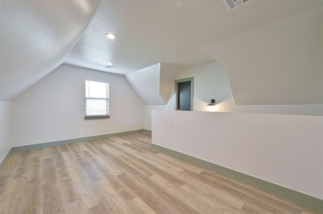 additional living space featuring lofted ceiling, baseboards, visible vents, and light wood-style floors