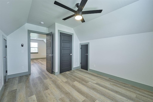 additional living space with light wood-style floors, lofted ceiling, ceiling fan, and baseboards