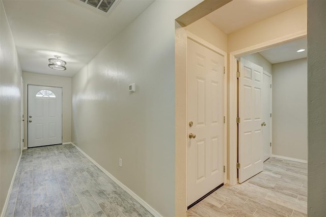 foyer with light wood-type flooring, baseboards, and visible vents