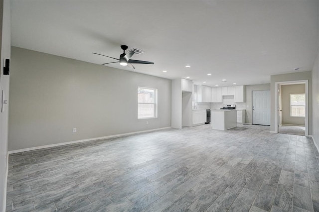 unfurnished living room with baseboards, light wood-style flooring, visible vents, and a ceiling fan