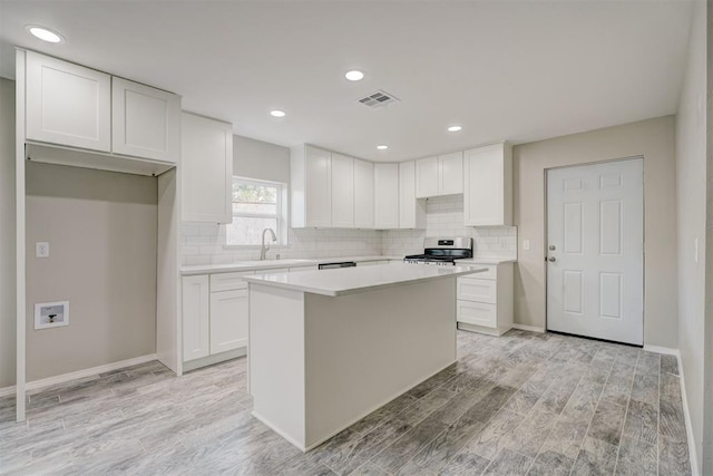 kitchen with stainless steel range oven, light wood finished floors, a kitchen island, and a sink