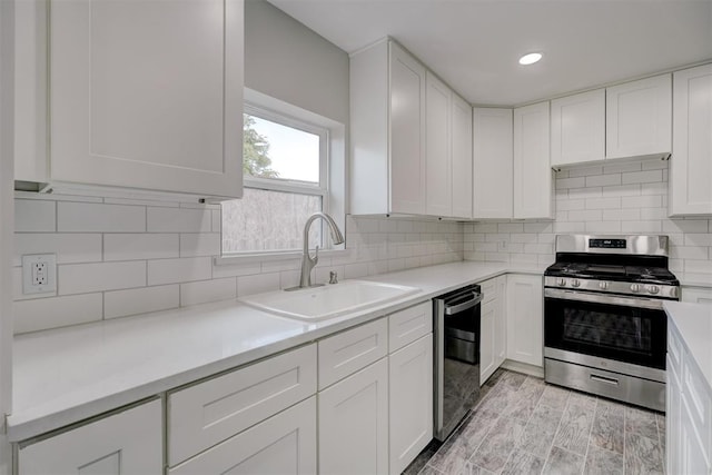 kitchen featuring dishwashing machine, a sink, white cabinetry, tasteful backsplash, and stainless steel range with gas stovetop