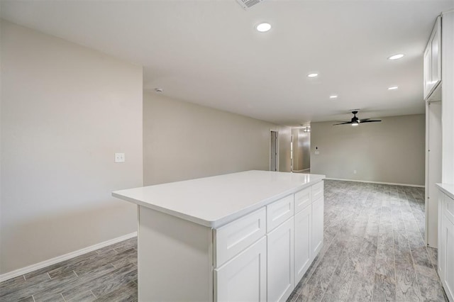 kitchen featuring recessed lighting, a kitchen island, white cabinets, light countertops, and light wood finished floors