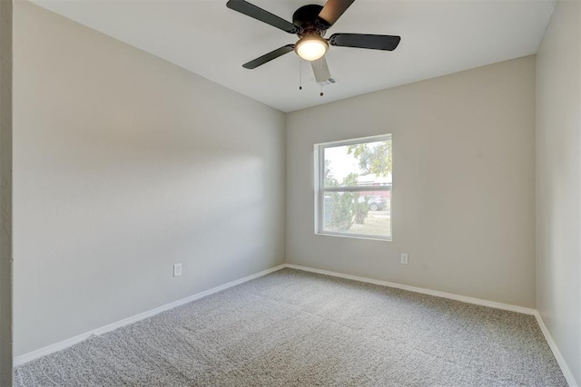 carpeted spare room with a ceiling fan and baseboards