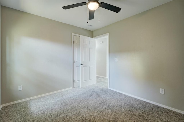 carpeted empty room featuring ceiling fan and baseboards