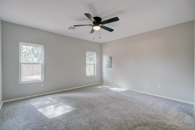 unfurnished room with carpet flooring, a ceiling fan, baseboards, visible vents, and electric panel