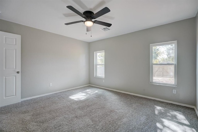 carpeted spare room featuring a ceiling fan, visible vents, and baseboards