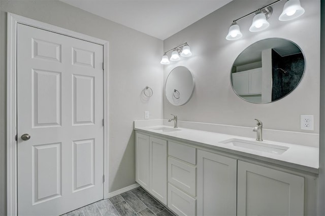 bathroom with double vanity, wood tiled floor, baseboards, and a sink