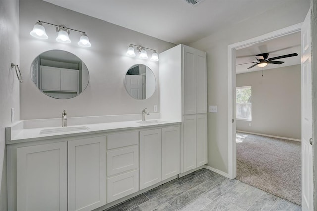 bathroom with ceiling fan, double vanity, a sink, and baseboards