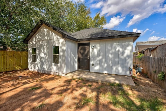 view of front facade with a shingled roof and a fenced backyard