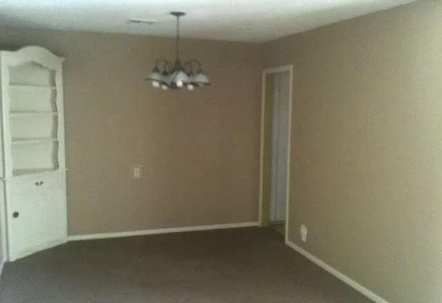 unfurnished room with baseboards and an inviting chandelier