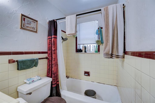 bathroom with toilet, shower / bath combo, tile walls, wainscoting, and a textured wall