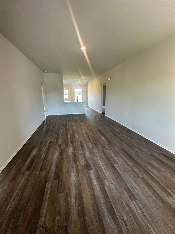 43067 Wagon Trl, Shawnee, OK 74804 - unfurnished living room with dark wood-style flooring and baseboards