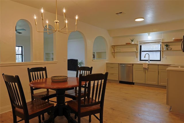 dining space featuring light wood-type flooring, arched walkways, a healthy amount of sunlight, and visible vents