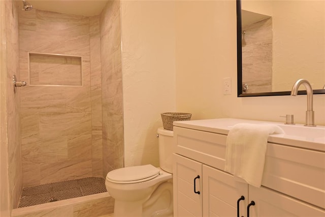 bathroom with tiled shower, vanity, and toilet