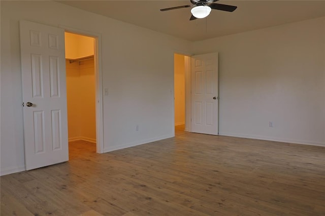 spare room with wood finished floors, a ceiling fan, and baseboards