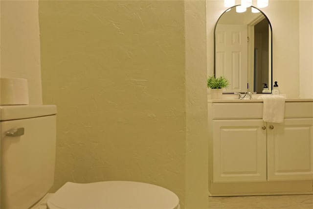 bathroom featuring a textured wall, vanity, and toilet