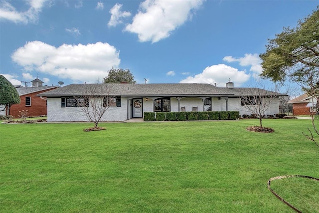 rear view of property with a lawn and brick siding