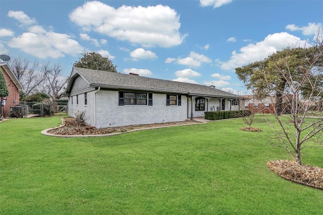 ranch-style home with a front yard, brick siding, and fence