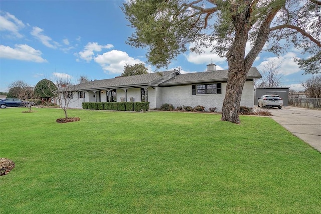 ranch-style house featuring a front yard, driveway, and a chimney