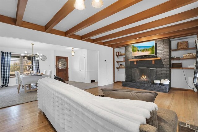 living room featuring hardwood / wood-style floors, a fireplace, a chandelier, and beamed ceiling