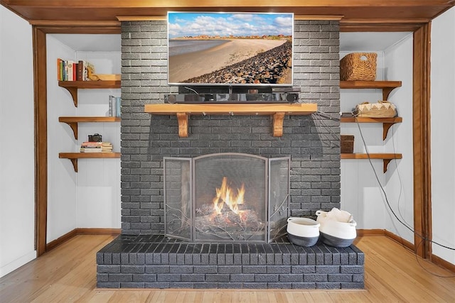 details featuring a brick fireplace, baseboards, and wood finished floors