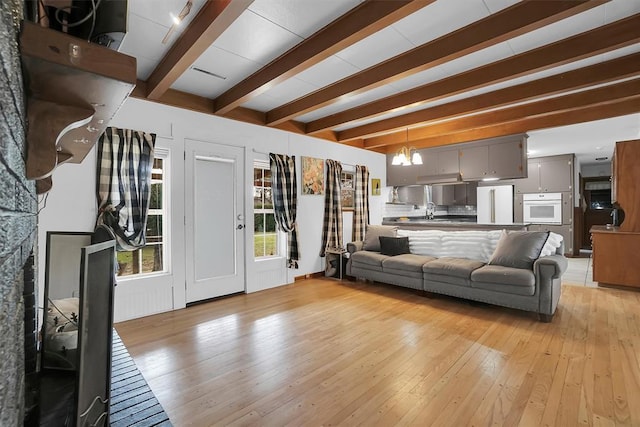 living area with light wood-style flooring, a chandelier, and beam ceiling