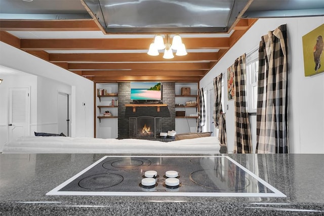 room details with a brick fireplace, beam ceiling, a notable chandelier, and black electric cooktop