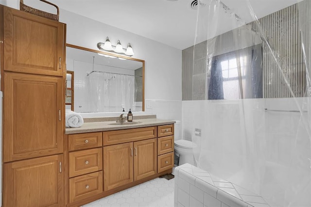 full bath with curtained shower, tile walls, toilet, and vanity