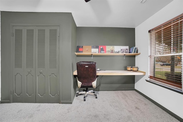 carpeted office featuring built in desk and baseboards