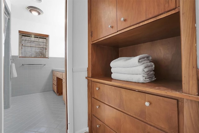 bathroom featuring a wainscoted wall, vanity, tile walls, and tile patterned floors