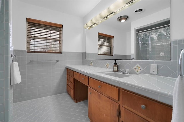 full bathroom with visible vents, a wainscoted wall, tile patterned floors, vanity, and tile walls