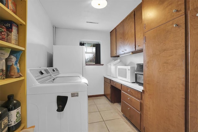 clothes washing area with light tile patterned floors, cabinet space, baseboards, visible vents, and washer and dryer