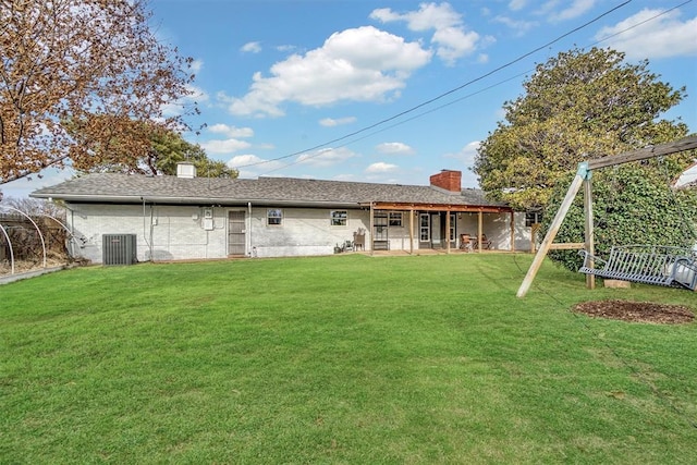 rear view of property featuring central air condition unit, a chimney, and a yard