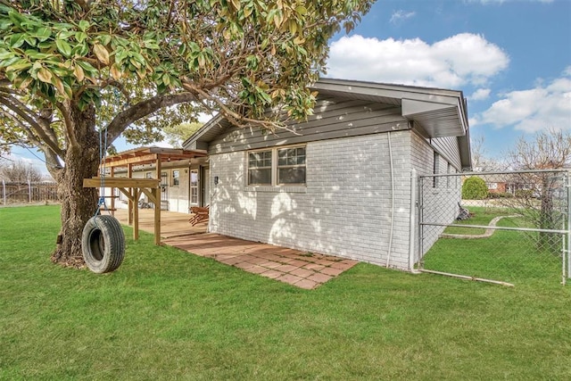 exterior space with a yard, fence, and brick siding