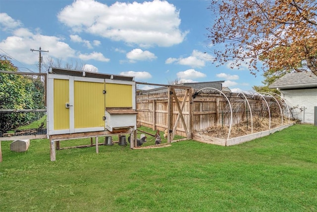 view of yard featuring an outbuilding, a vegetable garden, and fence