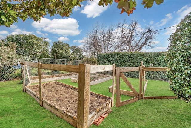 view of gate with a vegetable garden, a yard, and fence