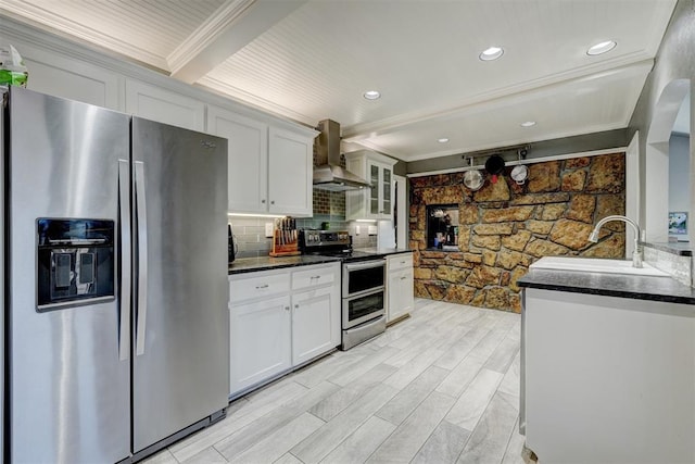 kitchen with white cabinets, ornamental molding, beamed ceiling, stainless steel appliances, and wall chimney range hood