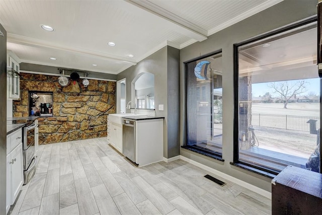 kitchen featuring stainless steel appliances, white cabinetry, visible vents, dark countertops, and crown molding