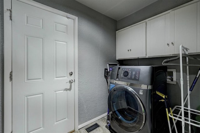 laundry area featuring a textured wall, visible vents, baseboards, cabinet space, and washer / dryer