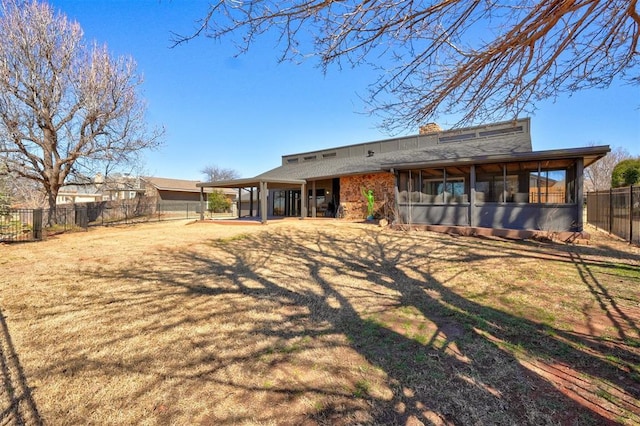 rear view of house with a lawn, a patio, a sunroom, a fenced backyard, and a chimney