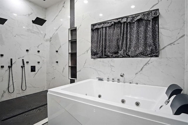 full bath featuring a whirlpool tub, tile walls, a marble finish shower, and stone wall