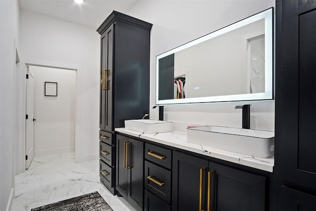 full bath with marble finish floor, baseboards, a walk in closet, and a sink