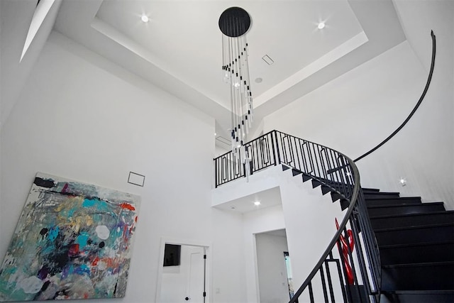 stairway with recessed lighting, a raised ceiling, and a high ceiling