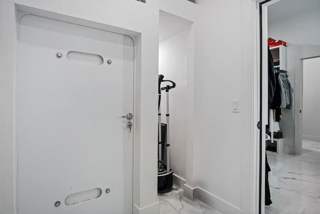 bathroom featuring marble finish floor, a spacious closet, and baseboards