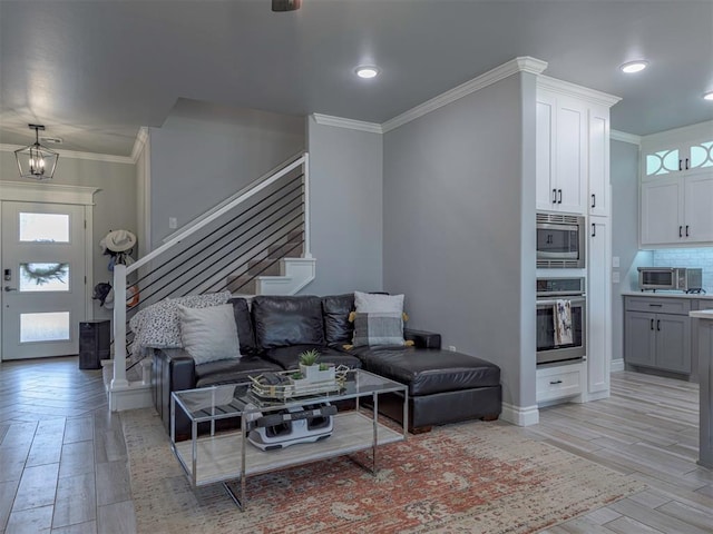 living area with a chandelier, light wood-style floors, stairs, baseboards, and crown molding