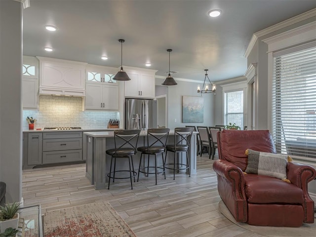 kitchen featuring a breakfast bar area, tasteful backsplash, gray cabinets, appliances with stainless steel finishes, and open floor plan