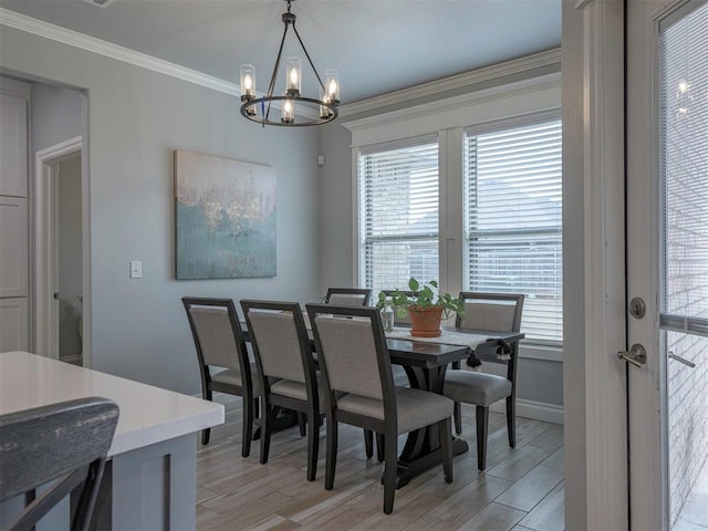 dining room featuring light wood finished floors, baseboards, a chandelier, and crown molding