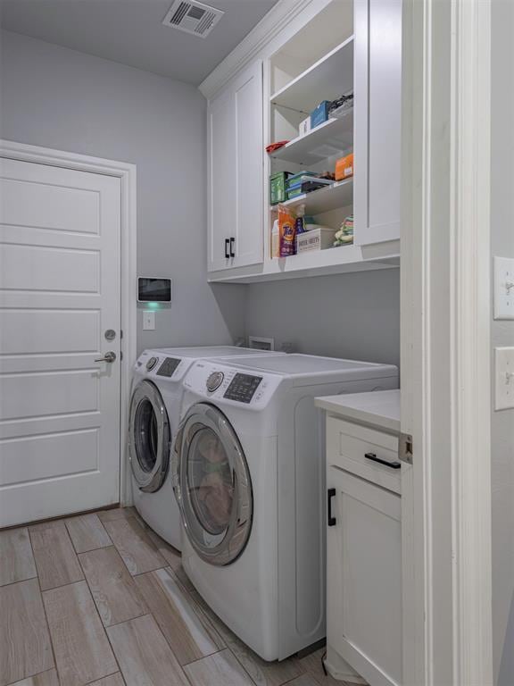 washroom with independent washer and dryer, cabinet space, visible vents, and wood tiled floor