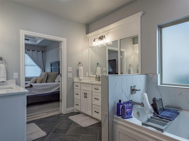 ensuite bathroom featuring a healthy amount of sunlight, connected bathroom, vanity, and a bath